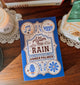 Book titled 'After the Rain' by Amber Palmer on a wooden surface with decorative elements.