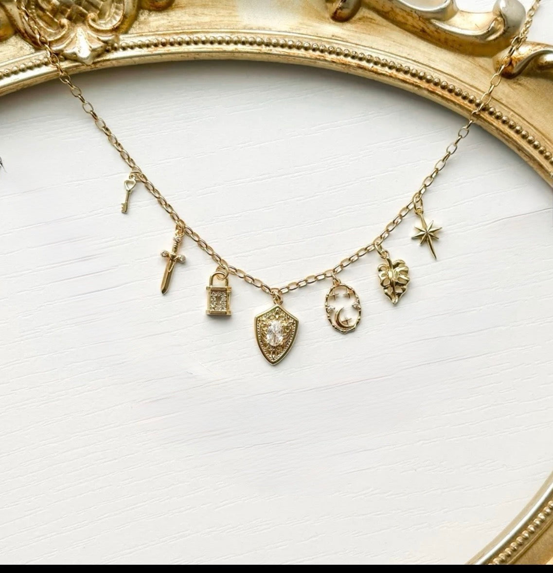 Gold necklace with various charms on a white background