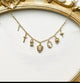 Gold necklace with various charms on a white background