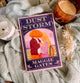 Book titled 'Dust Storm' by Maggie Gates on a textured surface with a candle and decorative elements.