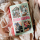 Book titled 'Storm Warning' by Ella Embers on a soft pink fabric background