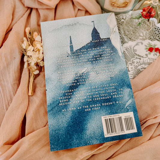 Book titled 'Heart of Chaos' by Madeleine Eliot on a soft fabric background with a candle and flowers.