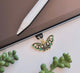 Butterfly-shaped phone charm on a laptop with green plants in the foreground dust plug 