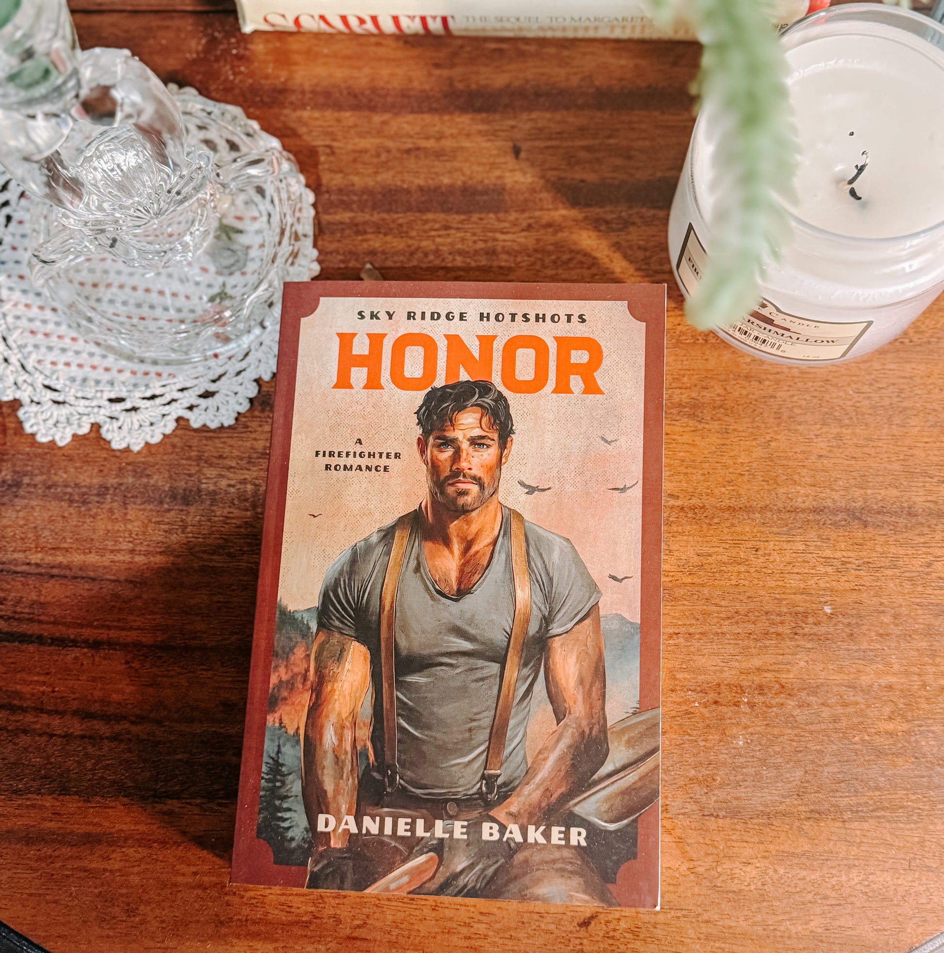 Book titled 'Honor' by Danielle Baker on a wooden surface with decorative items.
