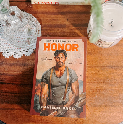 Book titled 'Honor' by Danielle Baker on a wooden surface with decorative items.