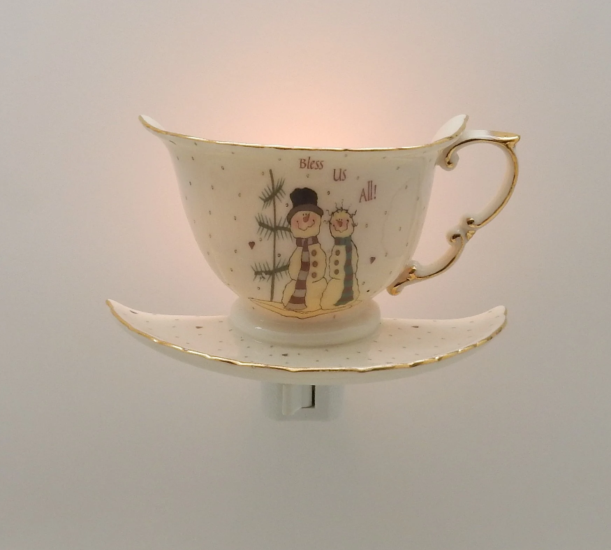 Decorative ceramic cup and saucer with snowmen design on a plain background night light 