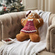 Gingerbread plush toy on a couch with a Christmas tree in the background
