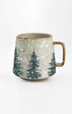 Ceramic mug with winter scene of trees and snow on a white background
