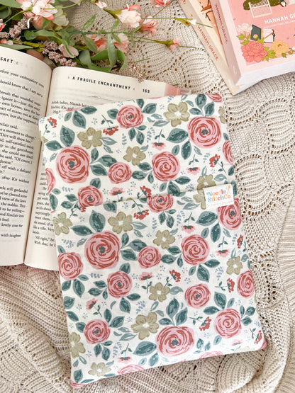 Floral notebook on a textured surface with an open book and flowers.