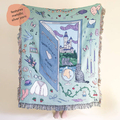Decorative blanket with illustrations of a book, castle, and various objects on a light blue background. Book lover blanket 